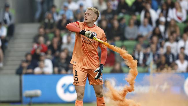 Tom Glover with one of the flares thrown onto the pitch in the Melbourne derby. Picture: Getty Images