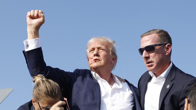 Mr Trump holds a fist aloft as he is rushed offstage.