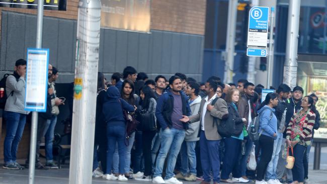 Commuters sit waiting at a bus stop on Railway Rd Burwood during today’s bus strike. Picture: John Grainger