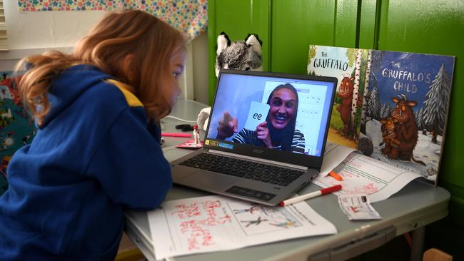 Five-year-old Lois Copley-Jones watches an online phonics lesson on a laptop in her bedroom in Newcastle-under-Lyme, England. Picture: Getty Images