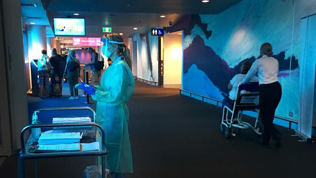 A staff member wearing protective medical clothing is available at Brisbane Airport to give advice to passengers. Picture: Getty Images