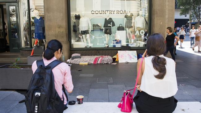 Workers sit outside the QVB which is lined with homeless people who have set up places to sleep. Picture: Dylan Robinson