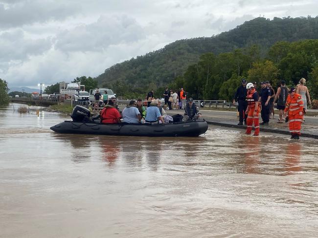 Cairns flood 2023: Royal Australian Navy personnel work with civilian emergency services to evacuate members of the public from Holloways Beach using a stretch of the Captain Cook Highway near the Barron River Bridge. Picture: Supplied