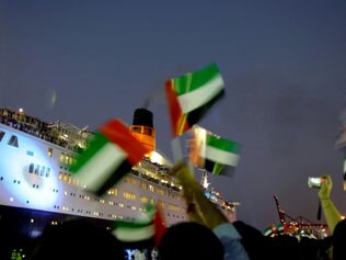 Warm welcome ... residents of Dubai wave British and Emirati flags as the famous cruise liner Queen Elizabeth 2 arrives at its final destination in Dubai / AFP