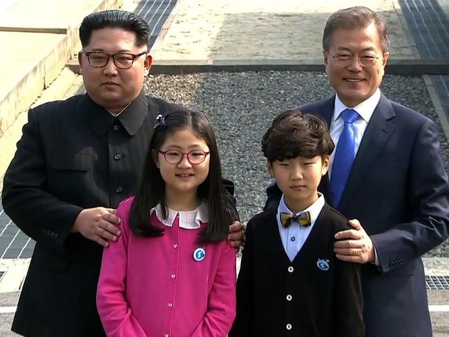 The Korean leaders pose with children as they meet at the Military Demarcation Line that divides their countries at Panmunjom. picture: Korean Broadcasting Service/AFP