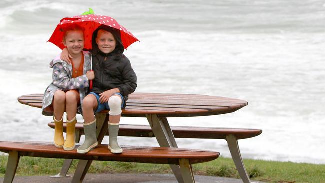 Baylie Britz, 7, and her brother Beau Britz, 5, huddle under an umbrella. Picture: Mike Batterham