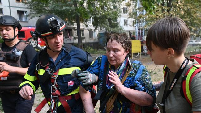 Ukrainian rescuers help an injured woman to leave the site of a missile attack in Kharkiv. Picture: Sergey Bobok / AFP