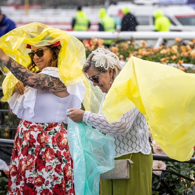 People prepare for rain at Flemington. Picture: Jake Nowakowski