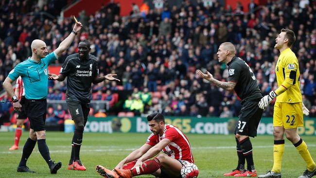 Referee Roger East (L) shows a yellow card to Liverpool's Martin Skrtel (2R).