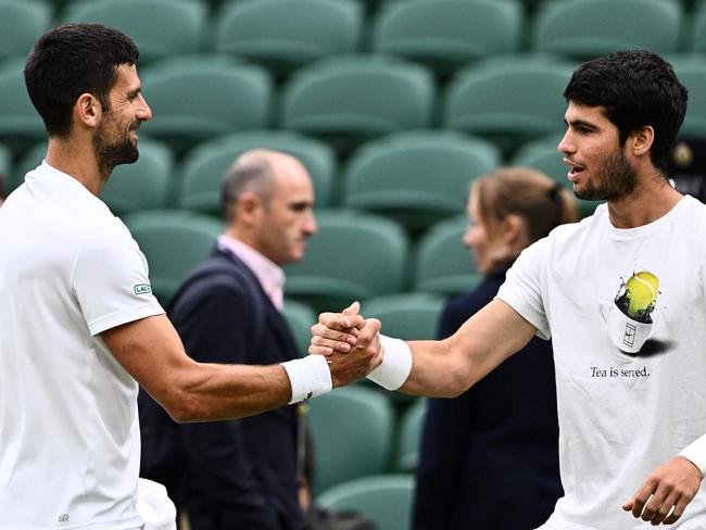 Serbia's Novak Djokovic (L) shakes hands with Spain's Carlos Alcaraz during a practise session prior to their men's singles semi-finals tennis matches on the twelfth day of the 2023 Wimbledon Championships at The All England Lawn Tennis Club in Wimbledon, southwest London, on July 14, 2023. (Photo by SEBASTIEN BOZON / AFP) / RESTRICTED TO EDITORIAL USE