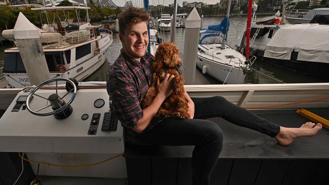 Brisbane hospital worker Samuel Scott, 22, on his houseboat with dog Ollie, has received both AstraZeneca jabs. Picture: Lyndon Mechielsen