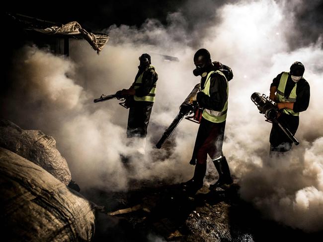 Officials wearing protective gear fumigate and disinfect the streets to help curb the spread of the Covid-19 coronavirus. Picture: AFP