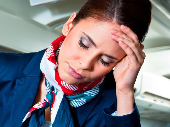 Young air stewardess suffering from headache on an airplane.