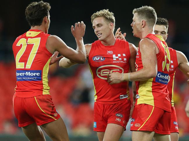 Darcy MacPherson of the Suns (center) celebrates with team mate Nick Holman (right) during the round eight AFL match between the Gold Coast Suns and the Melbourne Demons at Metricon Stadium on May 11, 2019 in Gold Coast, Australia. (Photo by Jono Searle/AFL Photos/Getty Images)