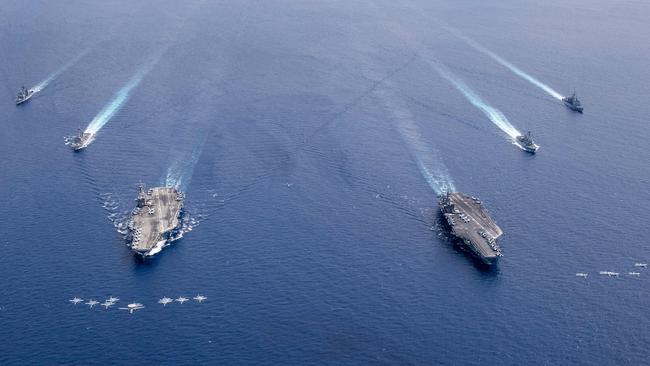 Aircraft from US Navy carrier air wings (lower left and right) fly in formation above the Nimitz Carrier Strike Force in the Indo-Pacific area last July. Picture: US Navy/AFP