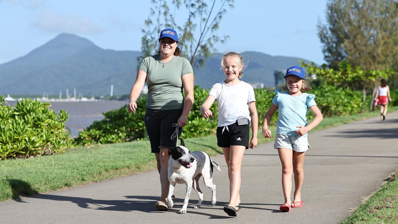 Evie walks along the Cairns Esplanade, where the One Walk event will be held, with mum Penny, sister Mae and dog Vally. Picture: Brendan Radke.