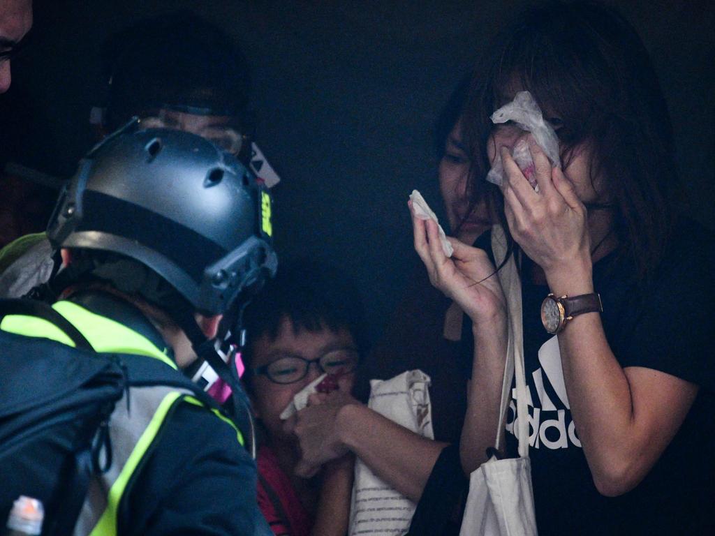 A child and other bystanders receive treatment by a medic volunteer, left, after police fired teargas to disperse protesters in Kowloon, Hong Kong. Picture: AFP