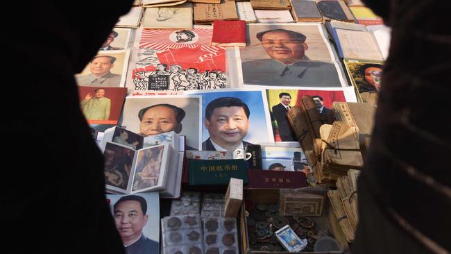 Customers look at posters of China's President Xi Jinping (centre) and late communist leader Mao Zedong (centre left and top right) at a market in Beijing. Picture: AFP