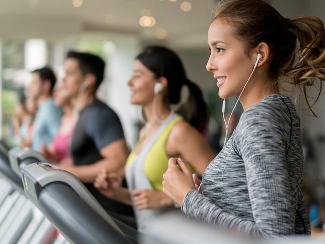 Portrait of a beautiful woman exercising at the gym running on a treadmill - fitness concepts