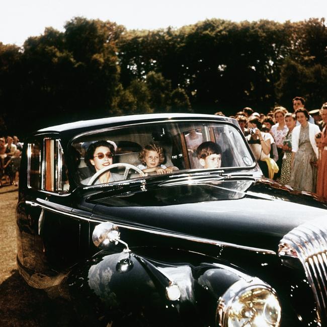 Queen Elizabeth II driving her children Prince Charles and Princess Anne at Windsor, watched by a group of onlookers in 1957. Picture: Hulton-Deutsch Collection/CORBIS/Getty Images