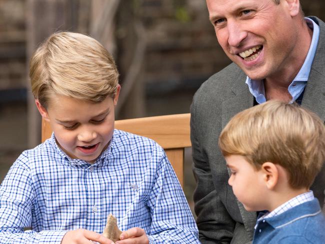 Prince William, Duke of Cambridge and Prince Louis watching as Prince George holds the tooth of a giant shark given to him by Sir David Attenborough. Picture: AFP