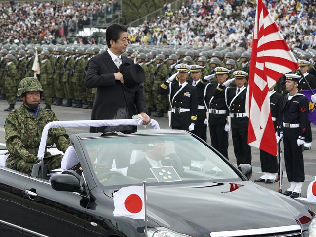 Japanese Prime Minister Shinzo Abe, center standing, reviews members of Japan Self-Defense Forces (SDF) during the Self-Defense Forces Day at Asaka Base in Asaka, north of Tokyo, Sunday, Oct. 14, 2018. Abe renewed his pledge to push for a revision to Japan's war-renouncing constitution at an annual defense review. (AP Photo/Eugene Hoshiko)