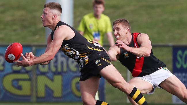 Tiger Eddie Cole fires off a handball under pressure from North Launceston’s Brad Cox-Goodyer. Picture: Nikki Davis-Jones