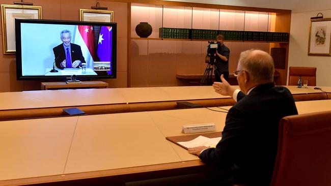 Scott Morrison and Singapore's Prime Minister Lee Hsien Loong, on screen, reach out for a virtual handshake on Monday. Picture: AFP