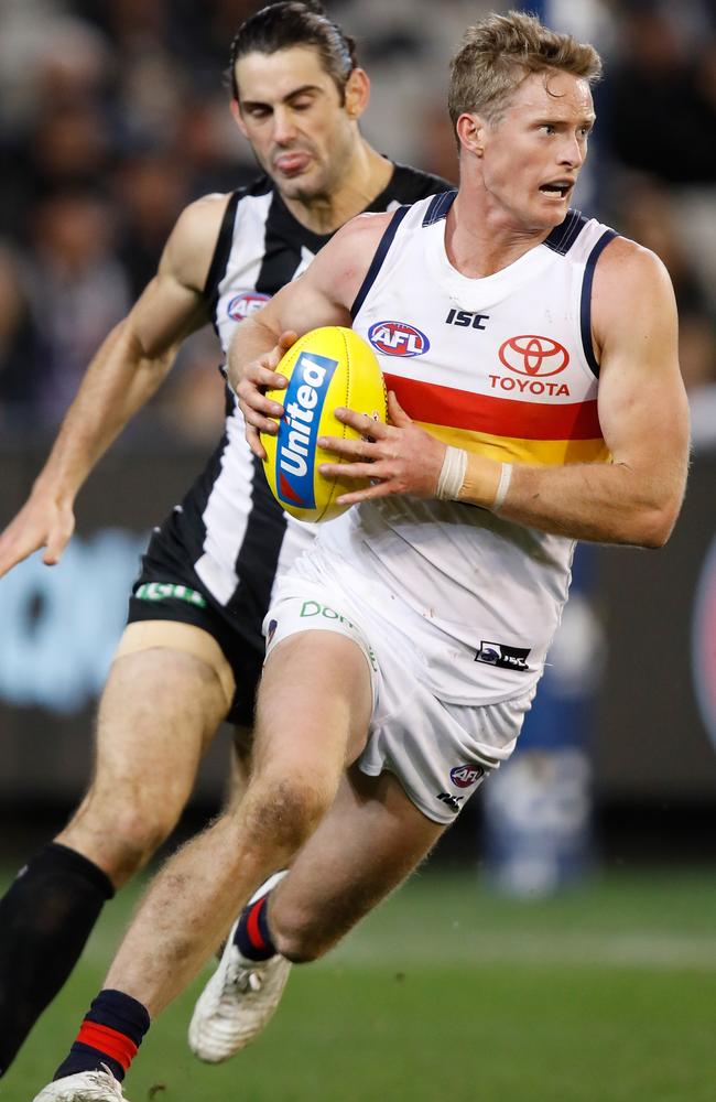 Alex Keath of the Crows is chased by Brodie Grundy of the Magpies.