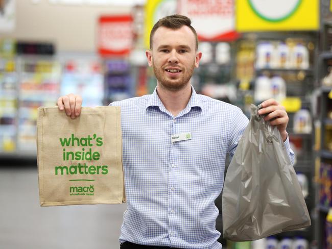 Woolies store manager Daniel Warden poses for photographs with an environmentally friendly reusable bag and a plastic shopping bag. Picture: AAP Image/Angelo Velardo