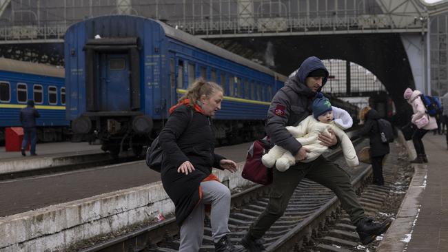 A family crosses the railway line in the Ukraine city of Lviv on Saturday. Picture: Getty Images