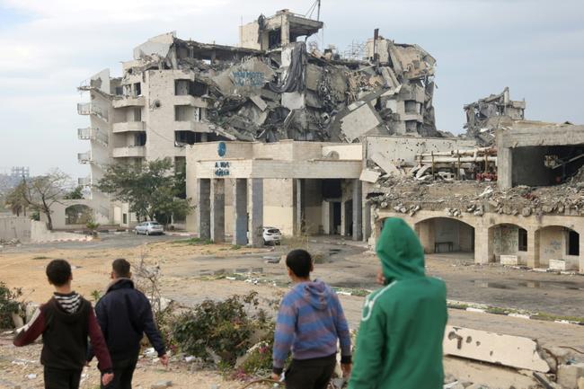 Women and children walk along a destroyed road in Beit Lahia, in the northern Gaza Strip