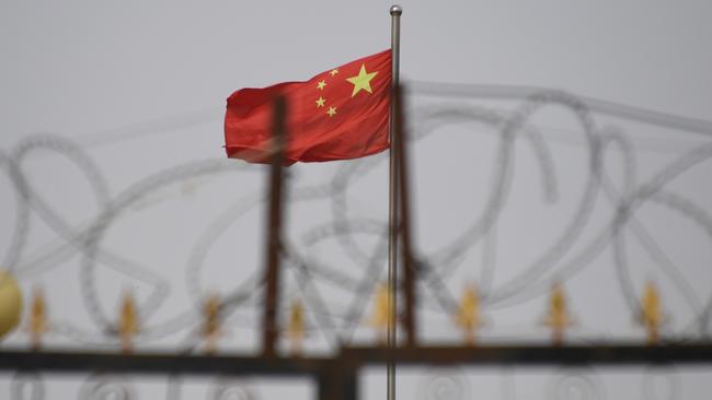 The Chinese flag behind razor wire at a housing compound in Yangisar, south of Kashgar, in China's western Xinjiang region. More than a million Muslims, Uighurs and other minorities have been locked up, brainwashed and abused over the past five years, according to a new book. Picture: AFP