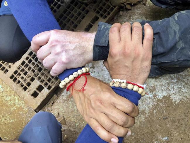 Rescuers hands locked with a caption that said: "We Thai and the international teams join forces to bring the young Wild Boars home". Picture: Thailand Navy SEAL Facebook page via AP