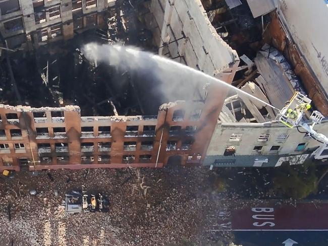 A Fire and Rescue NSW drone captures firefighters hosing down the ruins on Sunday.