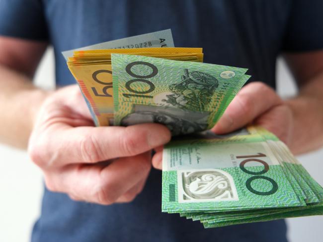 A man counting Australian dollar bills. A picture that describes buying, paying, handing out money, or showing money. Australian cash money generic