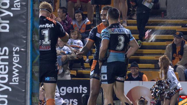 A projectile is thrown from the Leichhardt hill toward Tigers and Sharks players.
