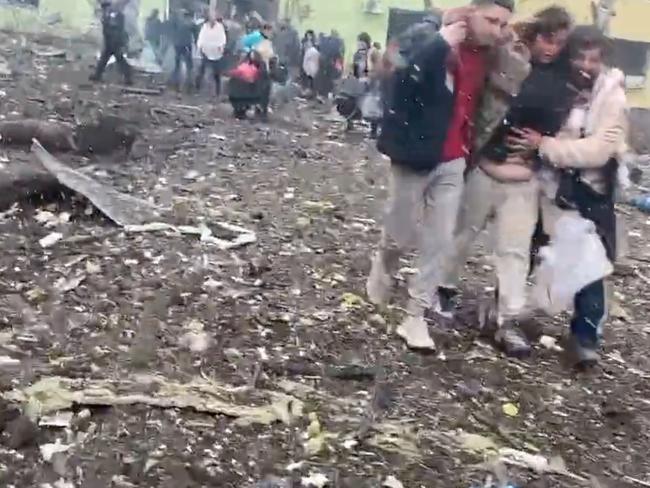 Injured people are helped from the bombed hospital.