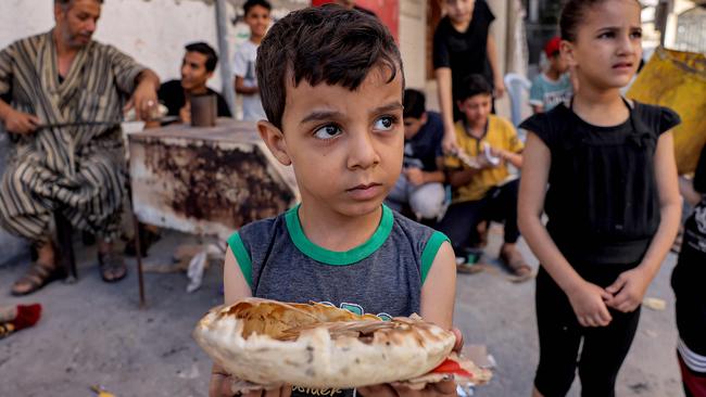 A boy lucks it with a fresh piece of bread in Rafah. Picture: AFP