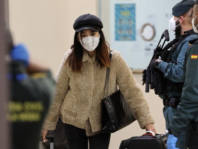 TOPSHOT - A passenger of a flight from Beijing leaves the terminal after landing at the Adolfo Suarez Madrid-Barajas airport in Barajas, on the outskirts of Madrid, on December 31, 2022. - The first flight from China after the reinstatement by Spain of health controls  on passengers from that country, in the midst of an explosion of covid cases, arrived in Madrid today evening. The passengers of the Air China CA 907 flight had to undergo temperature controls, present a negative covid test or prove that they were immunized with one of the vaccines approved in Spain upon arrival at Barajas, causing a scene not seen in months at the Madrid airport. (Photo by Pierre-Philippe Marcou / AFP)