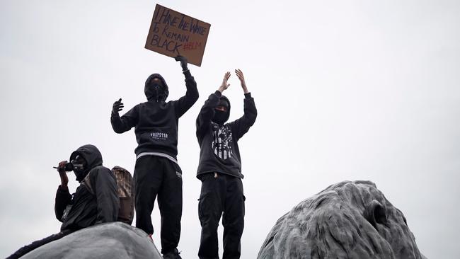 Activists wearing face masks stand on one of the Lion Statues in Trafalgar Square in London. Picture: AFP