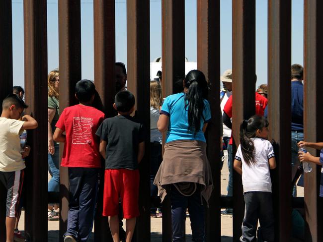 Children from the Anapra area observe a binational prayer performed by a group of religious presbyters on the border wall between Ciudad Juarez, Chihuahua state, Mexico and Sunland Park, New Mexico, US, on May 3, 2018. / AFP PHOTO / Herika Martinez