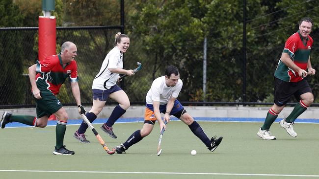 Charles Strickland (centre) of Queensland Police and Emergency services side against Redcliffe Red Schwarz team during the Brett Forte memorial hockey match played at the Mary Nairn Fields, Redcliffe, Saturday, October 6, 2018. Picture: AAP /Regi Varghese