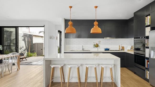 The pendant lighting contrasts the dark cabinetry in the kitchen and highlights the waterfall benchtop.