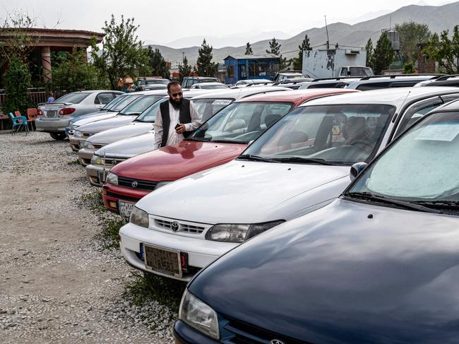 In this photograph taken on April 27, 2023, an Afghan car dealer waits for customers beside his parked Toyota Corolla cars, on the outskirts of Kabul. - Little is certain in Afghanistan -- armies invade and retreat, governments rise and fall -- but when the key of a Toyota Corolla turns in the ignition, the engine can be relied upon to roar to life. (Photo by Wakil KOHSAR / AFP) / To go with 'Afghanistan-Toyota-Corolla-Automobile-Transport', FOCUS by Joe STENSON and Qubad WALI