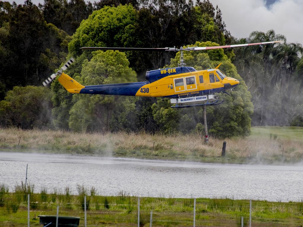 Smoke haze covers the Gold Coast Skyline from a grass fire at Carrara. A firefighting helicopter collects water from Judy Turners property in Carrara . Picture: Jerad Williams