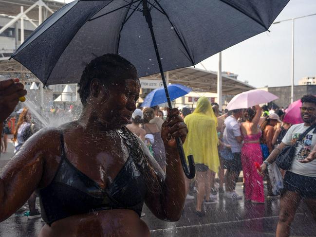 A woman cools off with a hose as Taylor Swift fans queue outside the Nilton Santos Olympic Stadium amid a heatwave in Rio de Janeiro ahead of the Eras Tour show. Picture: AFP