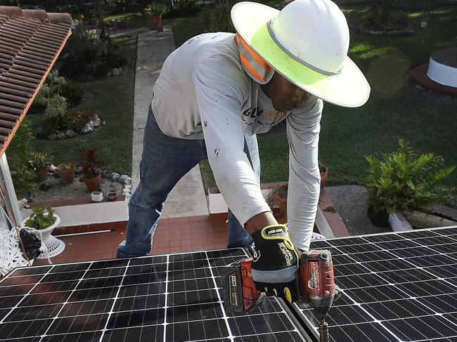 New tariffs on imported panels could slow the rate of solar expansion, but local and state policies requiring utilities to procure renewable energy will continue to help create a baseline market for solar power. Above, a worker installs a solar panel system on the roof of a home in Palmetto Bay, Fla., on Jan. 23. PHOTO: JOE RAEDLE/GETTY IMAGES