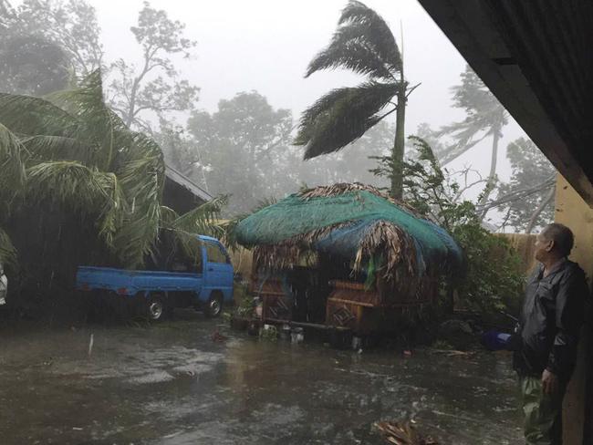 A man takes cover as strong winds and rain topple trees while Typhoon Haima lashes Narvacan, Ilocos Sur, northern Philippines. Picture: AP