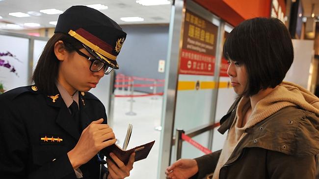 An airport security officer (L) checks a passenger's passport and boarding pass at Taipei Songshan Airport on March 10, 2014.